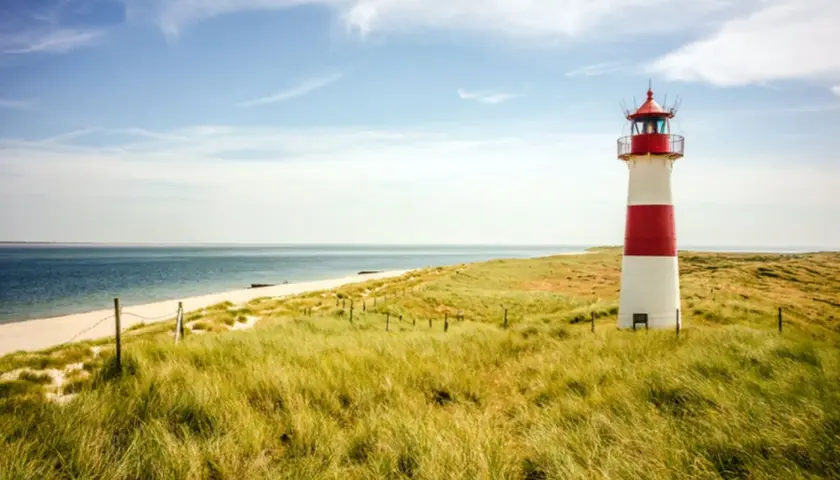 Leuchtturm am Strand mit Dünen, ein **Geheimtipp Urlaub August Deutschland**.