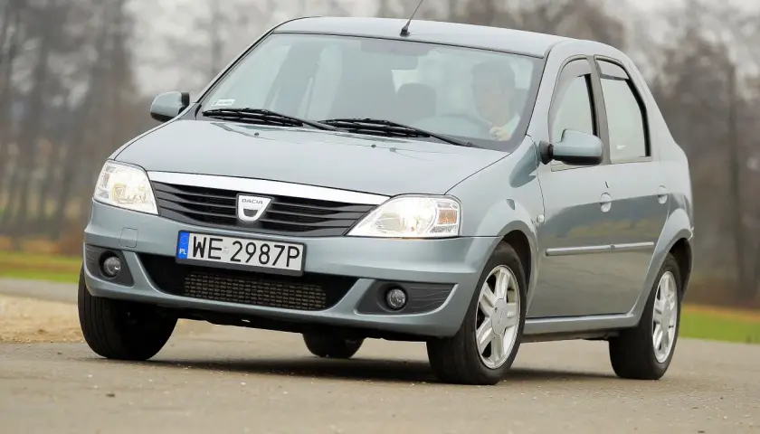 Szary Dacia Logan sedan z polskimi tablicami WE 2987P jedzie po drodze.