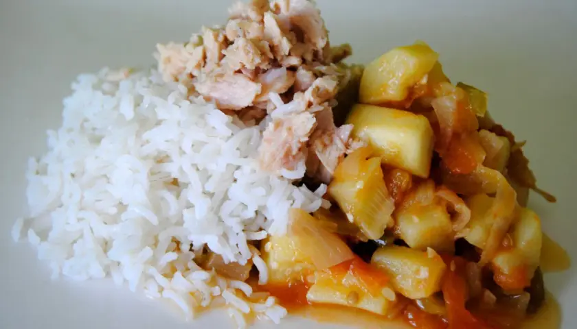 Arroz blanco con trozos de bonito de lata desmenuzado y un guiso de verduras en salsa de tomate.