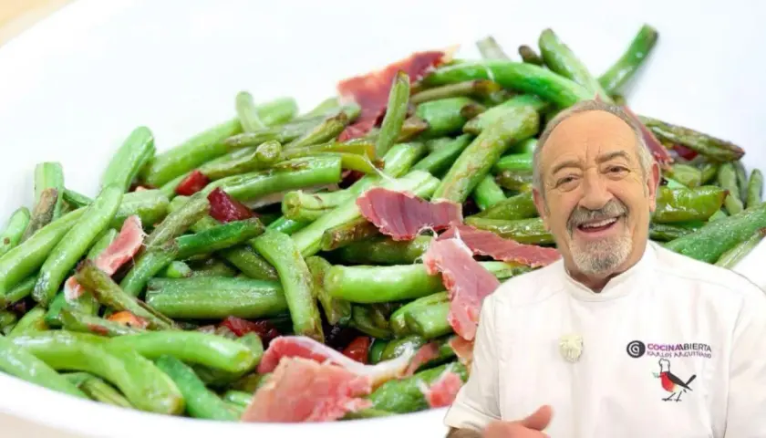 Un chef sonriente presenta un plato de judías verdes salteadas con trozos de jamón.
