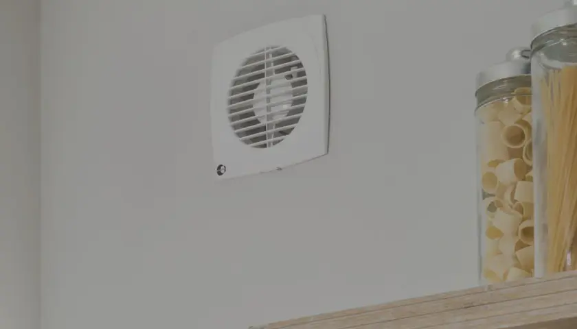 Aspiratore centrifugo o elicoidale bianco montato su parete grigia, accanto a barattoli di pasta.