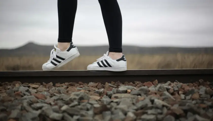 Białe adidasy Superstar to idealne buty do legginsów, świetnie wyglądają na tle torów kolejowych i krajobrazu.