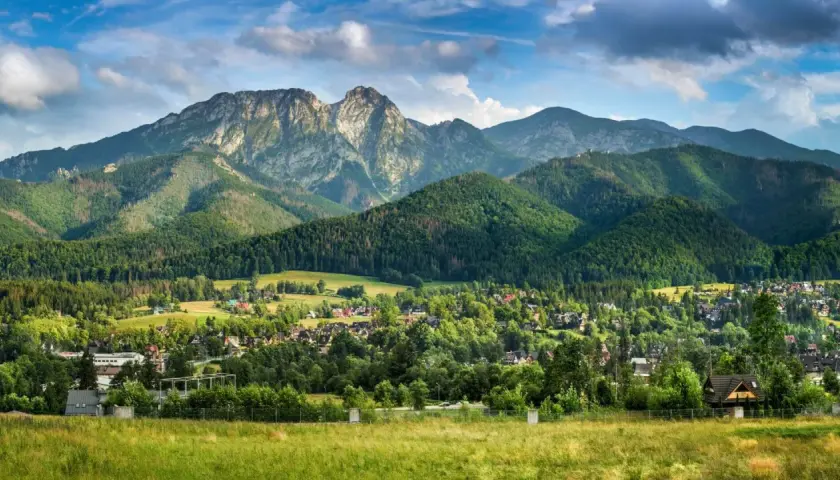 Majestatyczny Giewont, którego wysokość robi wrażenie, góruje nad zieloną doliną pełną domów i lasów.
