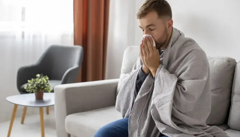 Mężczyzna owinięty kocem, z chusteczką przy nosie, może sugerować objawy choroby, ale czasem to tylko pozory, jak w przypadku zespołu Munchausena.