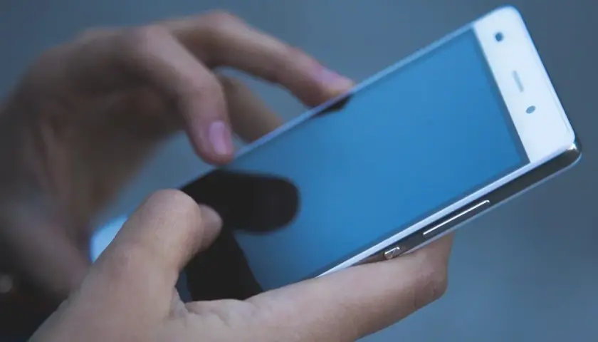 Dłonie trzymają telefon zmarłej osoby, przeglądając ostatnie wiadomości.