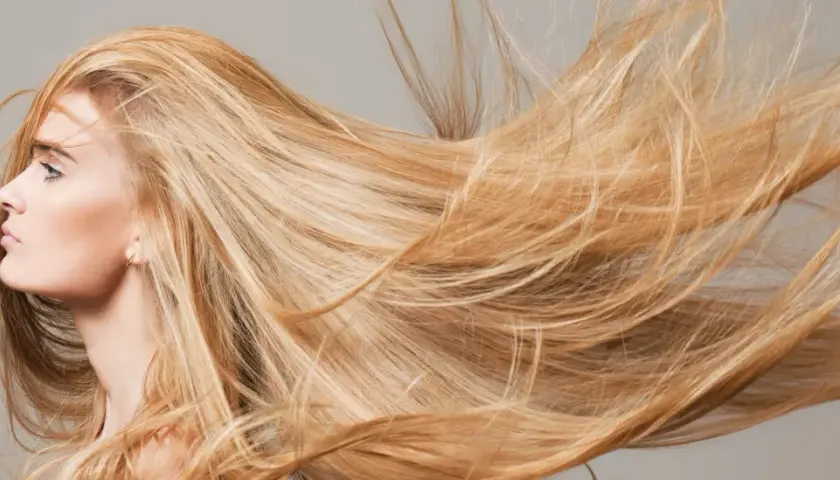 Mujer rubia con el pelo largo y suelto que parece que el pelo se aclara con el sol.