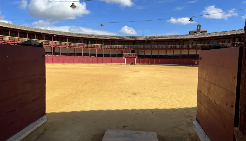 La plaza de toros de Toro, con su arena dorada y gradas rojas, espera bajo un cielo azul con nubes.