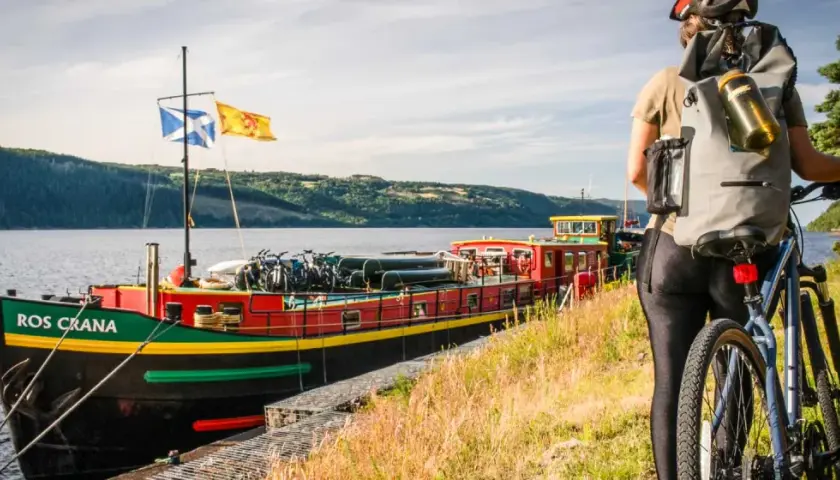 A cyclist pauses by a colorful barge loaded with bikes, ready for an adventure on the water.