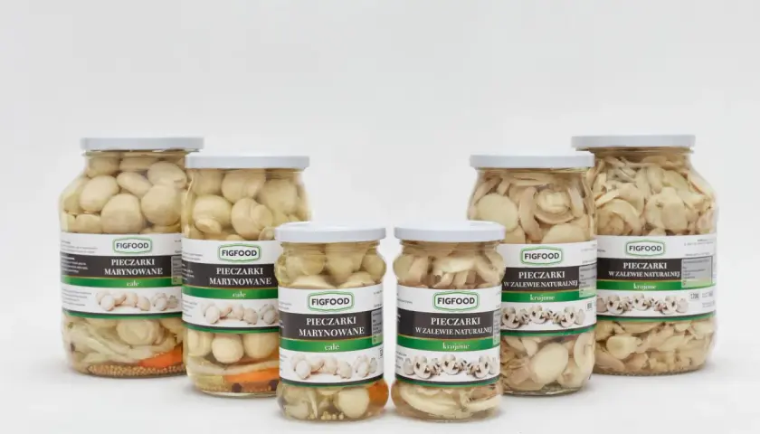 Sześć słoików z marynowanymi pieczarkami Figfood, w tym całe i krojone, na białym tle.