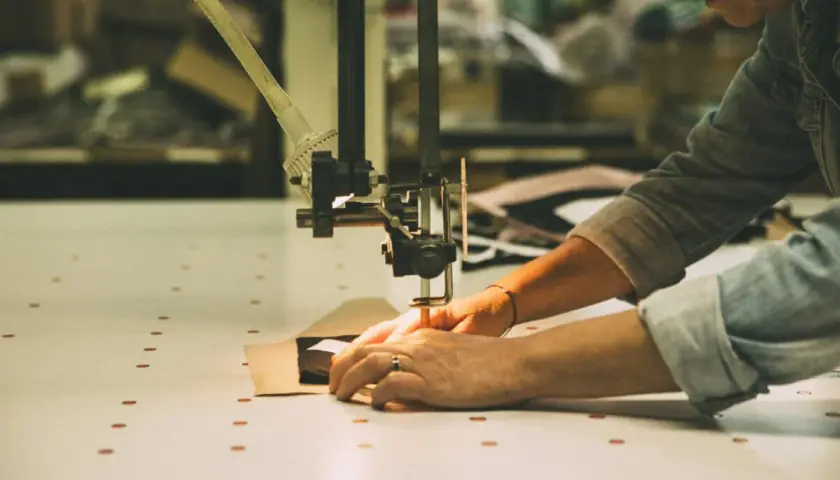 Mains guidant un tissu sous une machine à coudre, créant une pièce sans couture.