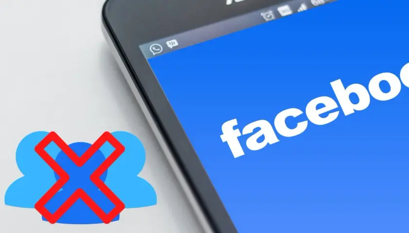 Chcesz wiedzieć, jak usunąć grupę na FB? Ikona z przekreślonymi ludzikami obok ekranu telefonu z logo Facebooka sugeruje rozwiązanie.