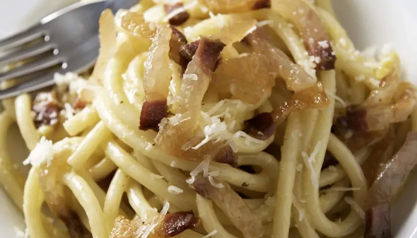 Ein Teller Pasta mit knusprigen Speckwürfeln, die zeigen, was ist Guanciale: luftgetrockneter Schweinebackenspeck, der für den authentischen Geschmack sorgt.
