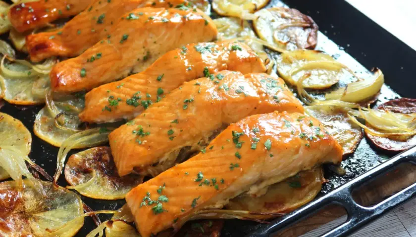 Filetes de salmón jugoso al horno con patatas y cebolla asadas.