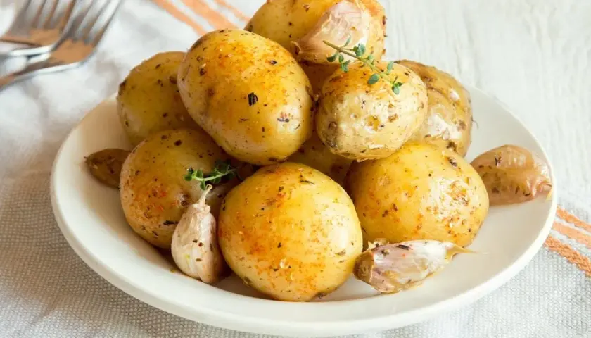 Patate al microonde in 3 minuti, condite con aglio e erbe aromatiche, pronte per essere gustate.