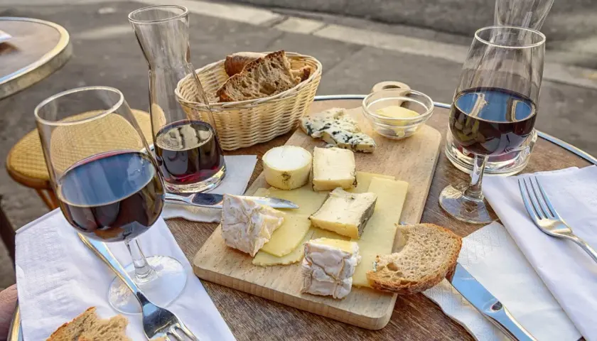 Assiette de fromages variés, pain croustillant et vin rouge, une dégustation parfaite pour accompagner un Saint-Émilion.