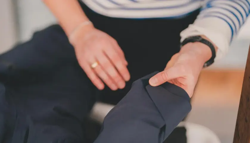 Dłonie przygotowują ciemną kurtkę do prania. Dowiedz się, jak prać Gore-Tex, by zachować jego właściwości.
