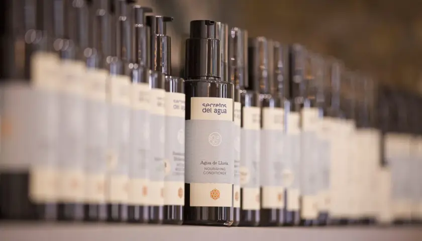 Botellas de acondicionador "Agua de Lluvia" de Secretos del Agua en un estante.