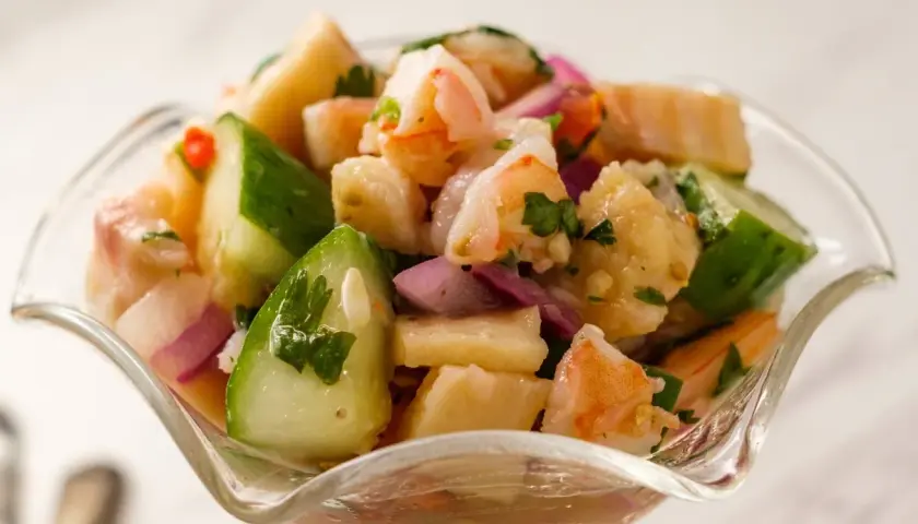 Orzeźwiające ceviche z krewetkami, ogórkiem, czerwoną cebulą i kolendrą w szklanej miseczce.