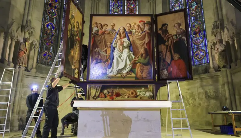 Mitarbeiter montieren einen Flügel des Altars in der Kirche. Buntglasfenster und Skulpturen zieren die Kathedrale.
