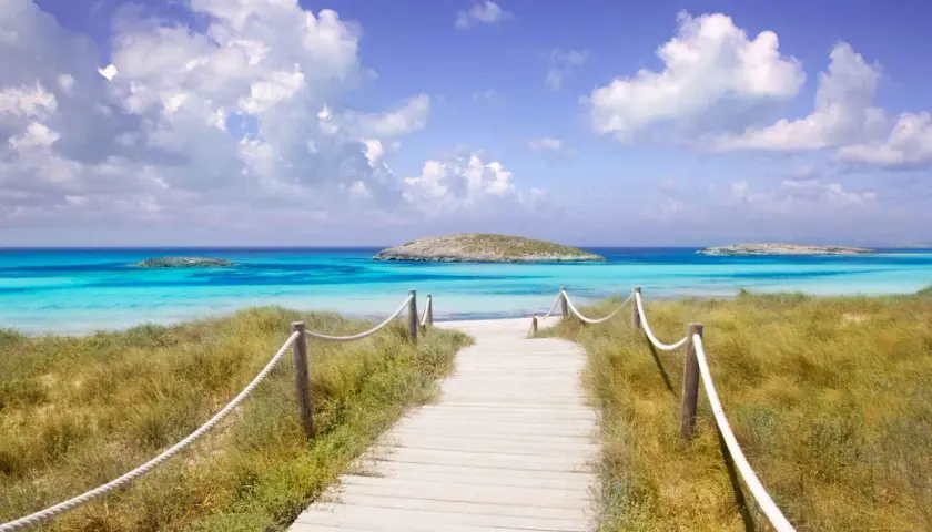 Camino de madera hacia las mejores playas del Levante. Aguas turquesas, arena blanca y un islote solitario.