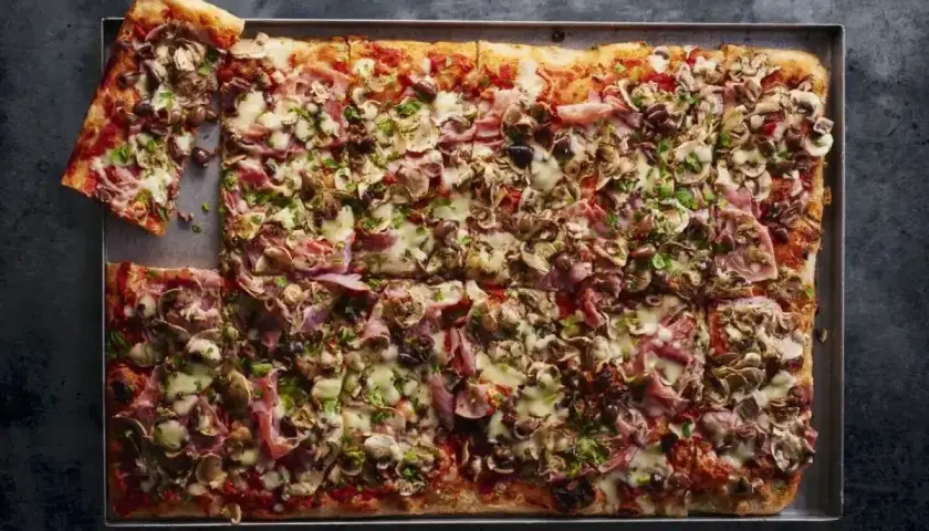 Pyszna pizza domowa przepis na blachę z szynką, pieczarkami i oliwkami. Idealna na rodzinne spotkanie.