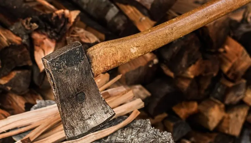 Axt liegt auf einem Stapel Brennholz. Der raummeter holz preis ist hier nicht ersichtlich, aber das Holz ist bereit zum Spalten.