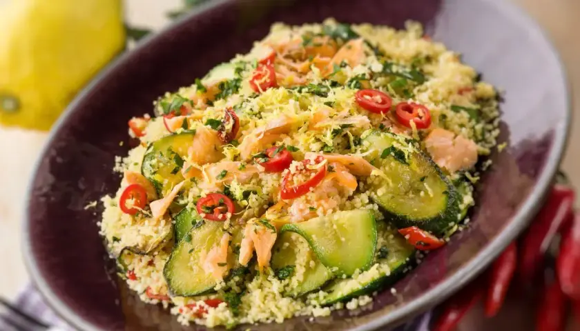 Un saporito cous cous con verdure, tonno e peperoncino, guarnito con scorza di limone e prezzemolo.
