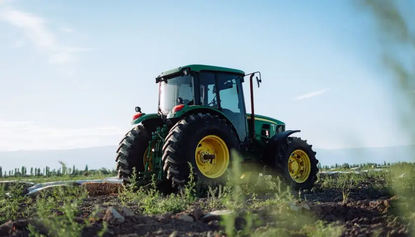 Zielony traktor John Deere na polu, gotowy do pracy. Właściwe płyny eksploatacyjne zapewniają jego niezawodność.