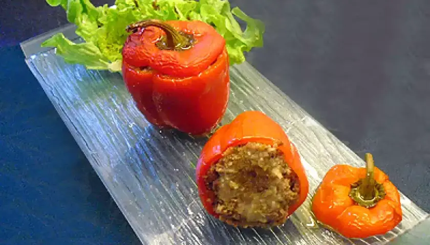 Poivrons farcis à la chair à saucisse, servis sur un plateau en verre avec une feuille de laitue.