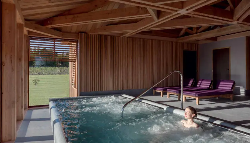 Détente dans un chateau spa à Bordeaux. Une femme profite d'un jacuzzi avec vue sur les vignes.
