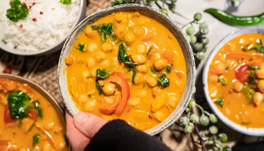 Ein köstliches veganes Curry mit Kichererbsen, Paprika und Spinat in cremiger Sauce, serviert mit Reis.