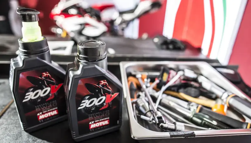 Dwie butelki oleju Motul 300V obok narzędzi. Czy Motul jest lepszy do motocykli sportowych?
