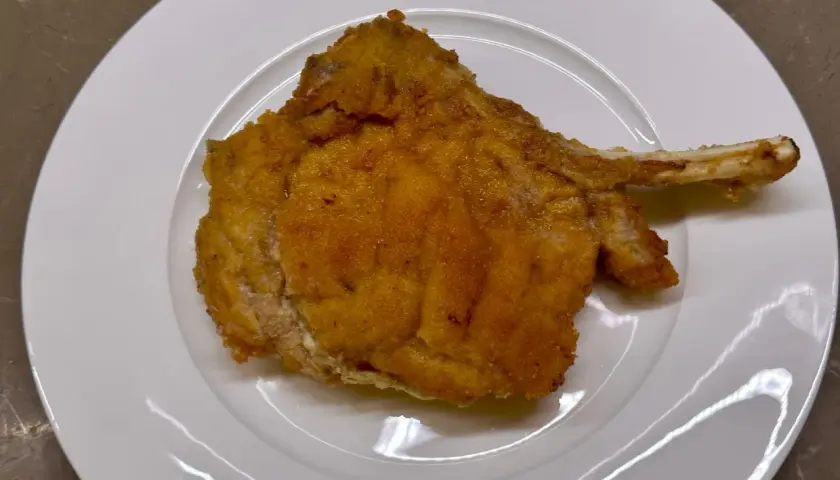Cotoletta alla valdostana dorata e croccante su piatto bianco, pronta per essere gustata.