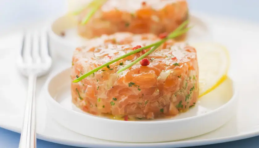 Deux tartares de saumon frais, garnis de ciboulette et de poivre rose, prêts à être dégustés. Parfait pour savoir que boire avec un tartare de saumon.