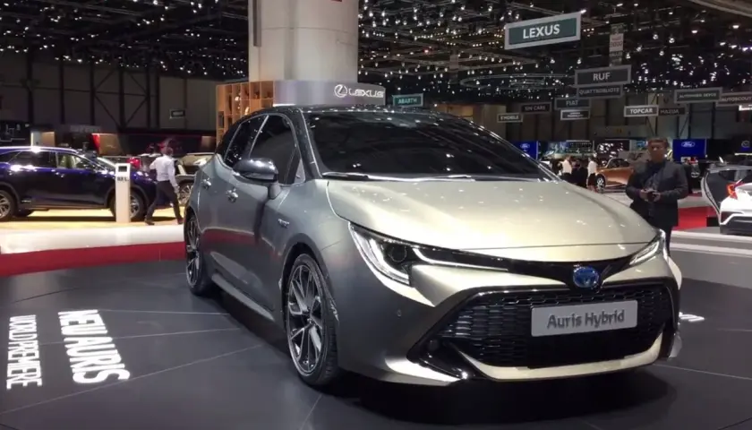 Elegancki, srebrny Auris Hybrid prezentowany na targach motoryzacyjnych. Na podłodze widoczny napis "NEW AURIS WORLD PREMIERE".