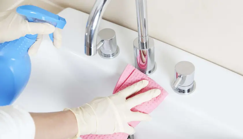 Mit Handschuhen und einem selbstgemachten Badreiniger wird das Waschbecken blitzblank.