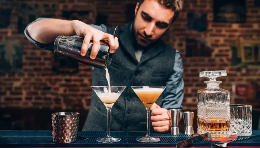 Barman przelewa drinka do kieliszka, tworząc idealną piankę z białka. Poznaj przyczyny mętnienia drinków typu sour.