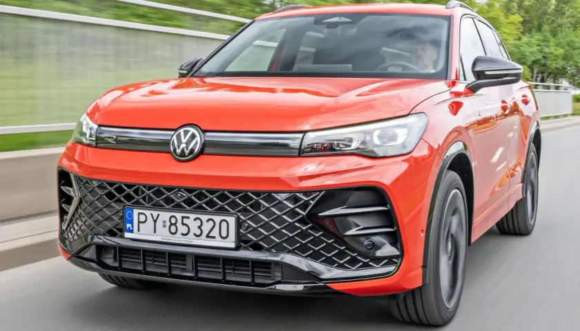 Nowy Tiguan w jaskrawym kolorze jedzie po drodze.
