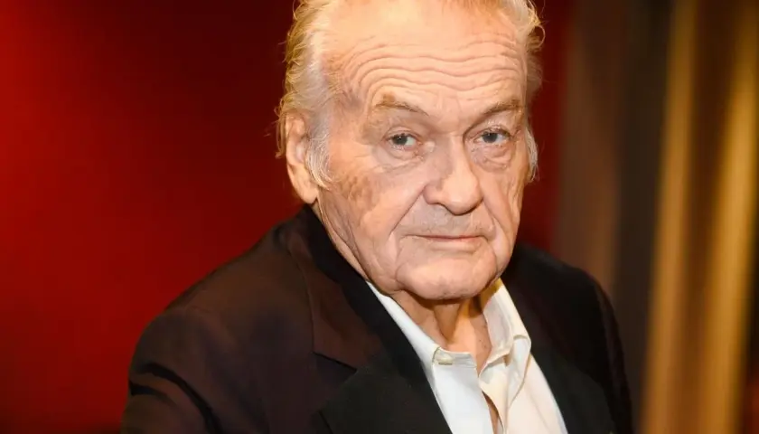 Jerzy Skolimowski, reżyser znany z wyrazistych filmów, na tle czerwonej kurtyny.