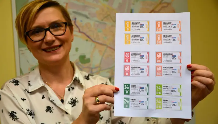 Kobieta prezentuje wydrukowane bilety ZTM Kielce. Na kartce widać różne rodzaje biletów jednorazowych, godzinnych i dobowych, z podanym cennikiem.
