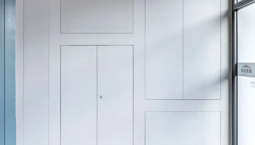 Pannelli a filo muro con ante in cartongesso, un design minimalista che nasconde accessi e vani.