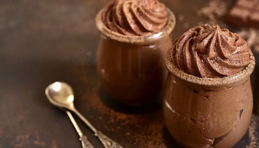 Délicieuse présentation de mousse au chocolat, garnie de cacao, prête à être dégustée avec des cuillères élégantes.