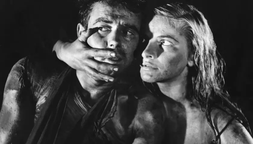 Dramatyczna scena z filmu Andrzeja Wajdy. Kobieta zakrywa usta mężczyźnie, ich twarze są spocone i brudne.