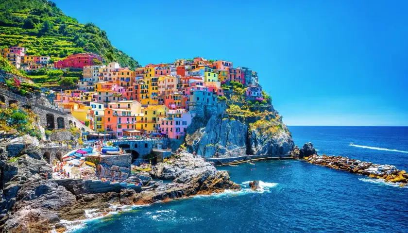 Village coloré accroché à la falaise, vue sur la mer bleue. Un gîte Cinque Terre parfait pour des vacances inoubliables.