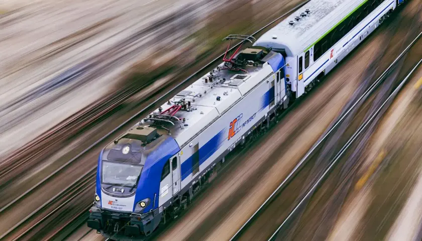 Pędzący pociąg PKP Intercity EU160 na torach, rozmyte tło sugeruje dużą prędkość.