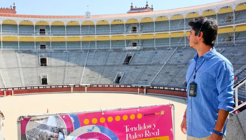 Un guía turístico en la plaza de toros de Madrid, con los tendidos y el Palco Real al fondo.