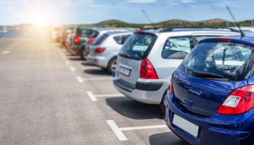Rząd zaparkowanych samochodów na parkingu, z niebieskim samochodem na pierwszym planie.