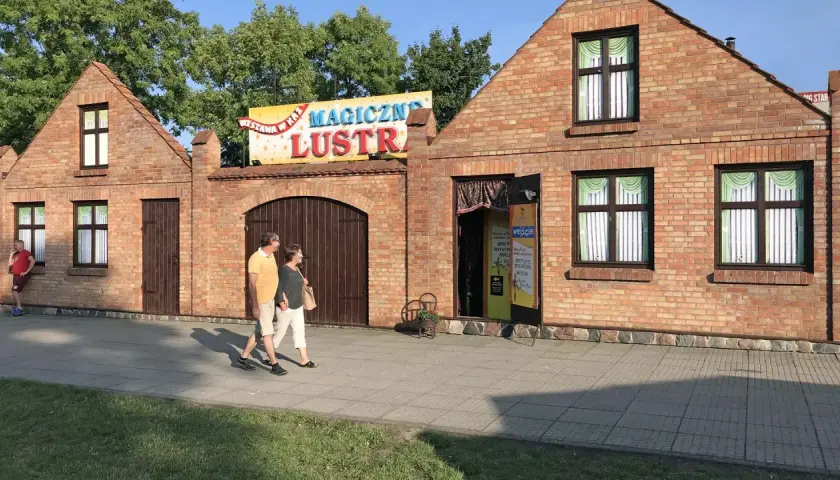 Para spaceruje obok budynku z napisem "Magiczne Lustra Łeba".