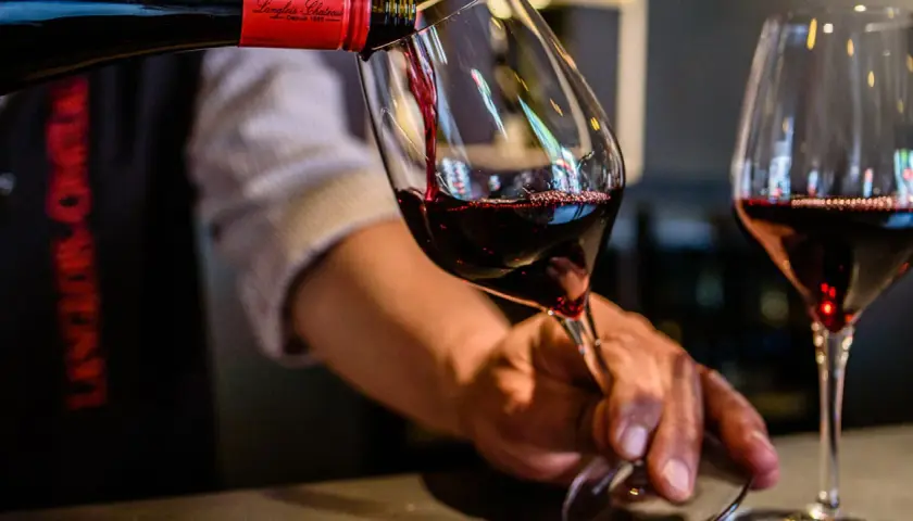 Service d'un vin rouge, idéalement servi à la bonne **température Saumur Champigny**. Le vin est versé dans un verre, avec une autre verre déjà rempli.