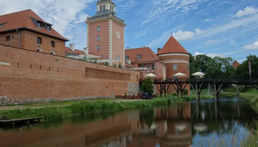 Zamek w Lidzbarku Warmińskim, z wieżą i fosą, to jedna z głównych atrakcji regionu.